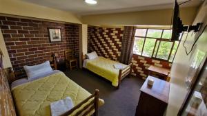 a bedroom with two beds and a brick wall at Mirador Backpackers B&B in Huaraz