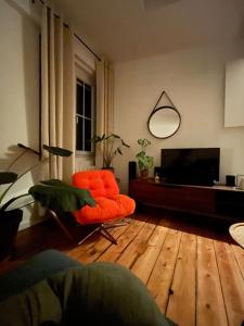 a living room with an orange chair and a television at L'Atelier Saint Michel in Bordeaux