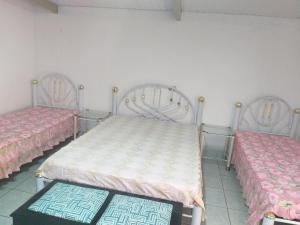 two beds in a room with pink and white sheets at Kitnet para 4 pessoas in Triunfo