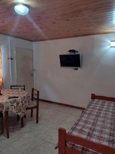 ein Zimmer mit einem Tisch und einem Fernseher an der Wand in der Unterkunft Cabañas Midelem in Chascomús