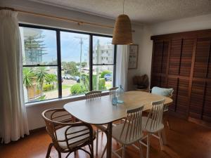 a dining room with a table and chairs and a large window at Pleasant View Apartment - Ocean View in Caloundra +9 photos
