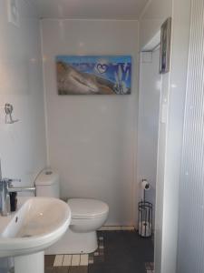 a bathroom with a white toilet and a sink at Round About in Parore