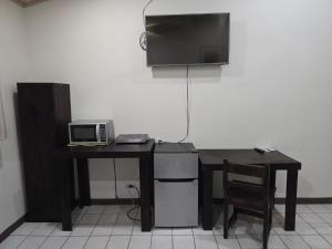 a desk with a microwave and a television on a wall at Hotel Don Fito in Golfito +39 photos