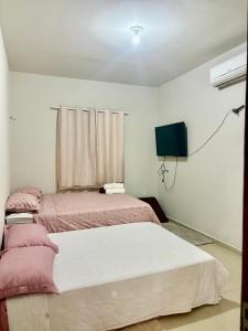 a bedroom with two beds and a flat screen tv at Temporada AK Freitas in Parnaíba