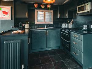 a kitchen with blue cabinets and a sink and a stove at The Game Keeper - Uk50611 in Sabden +7 photos