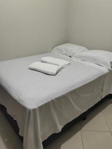 a bed with white sheets and towels on it at Quarto em Foz, ótima localização em casa familiar in Foz do Iguaçu