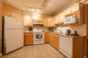 a kitchen with white appliances and wooden cabinets at Cozy 2BR-5BD Suite - Mountain Views - Htd Parking in Canmore