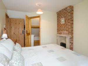 a bedroom with a white bed and a fireplace at The Stable in Foxham