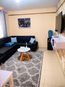 a living room with a black couch and a table at 1 Bedroom in Section 58 behind Kunste Hotel in Nakuru