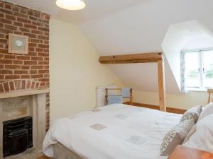 a bedroom with a bed and a brick fireplace at The Stable in Foxham