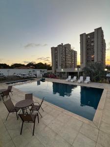 a swimming pool with tables and chairs and buildings at Torres dos Holandeses Vista Mar in São Luís