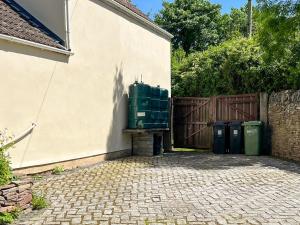 a building with two trash cans next to a fence at Commonwealth Cottage in Iron Acton