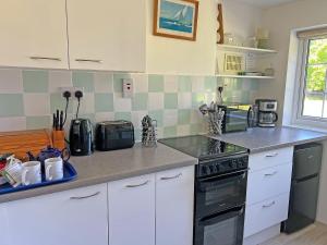 a kitchen with white cabinets and a black stove top oven at Commonwealth Cottage in Iron Acton