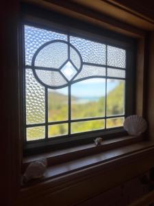 a window with a view of a field through it at Abel Tasman guest house in Marahau