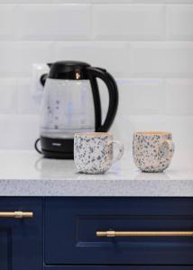 two cups sitting on a counter next to a toaster at LuxCity Apartment in the Center of Nowy Targ, FREE PARKING in Nowy Targ