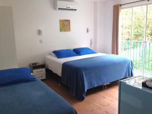 a bedroom with a bed with blue sheets and a window at The Hyperion Boutique Hotel in Florianópolis +58 photos