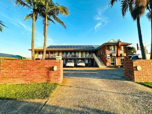 a large house with palm trees in front of it at Aussie Rest Motel in Cessnock