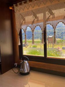 a tea kettle sitting on a table in front of a window at Cabañas Valles del Mañihuales in Villa Maniguales