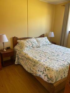 a bed in a bedroom with two lamps on tables at Cabañas Valles del Mañihuales in Villa Maniguales