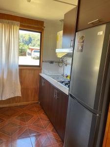 a kitchen with a stainless steel refrigerator and a window at Cabañas Valles del Mañihuales in Villa Maniguales +4 photos