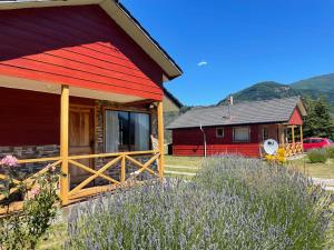 a house with a red roof and a yard with purple flowers at Cabañas Valles del Mañihuales in Villa Maniguales