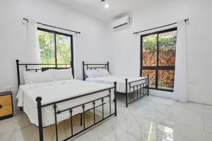 two beds in a white room with two windows at Sunset Havendale in Kingston