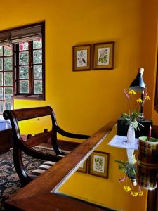 a yellow room with a wooden table and a bench at Abbotsford Prasada Bhawan in Nainital