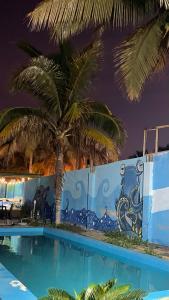 a swimming pool with a palm tree in front of a wall at Hostel Angeles del Mar in San Antonio