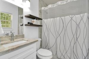 a white bathroom with a toilet and a sink at 2 BR Cottage Midtown Downtown EADO in Houston +25 photos