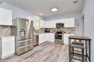 a kitchen with white cabinets and a stainless steel refrigerator at 2 BR Cottage Midtown Downtown EADO in Houston