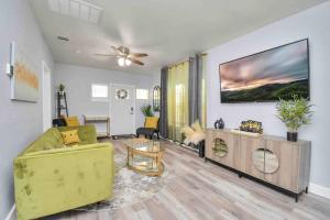a living room with a yellow couch and a tv at 2 BR Cottage Midtown Downtown EADO in Houston