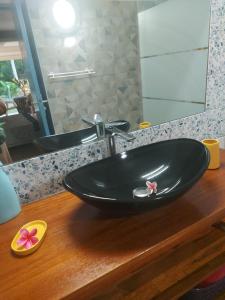 a black sink on a wooden counter in a bathroom at Studios Soleil du Sud in Sainte-Anne