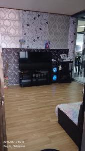 a living room with a television and a wooden floor at Ingeritch Cabin Transient and Homestay in Baguio