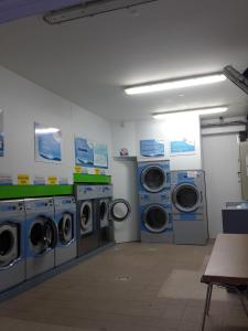a laundry room with three washing machines and a washer and dryer at Studios Soleil du Sud in Sainte-Anne