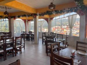 a restaurant with tables and chairs and large windows at Hotel Los Arcos in Tlalpujahua de Rayón