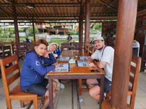 three people sitting at a table playing a board game at Sunset Homestay in Sapit