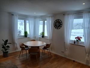 a dining room with a table and chairs and windows at Ferienwohnung Waldlichtung in Simmersfeld +18 photos