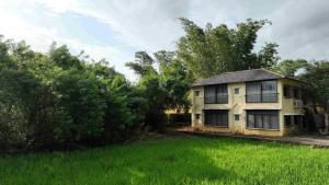 a yellow house in a field of green grass at Saguna Baug Agro Tourism in Neral
