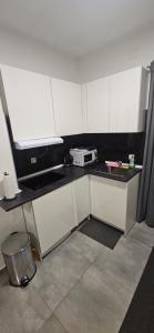 a small kitchen with white cabinets and a microwave at Apartman MAGDALENA in Sesvete
