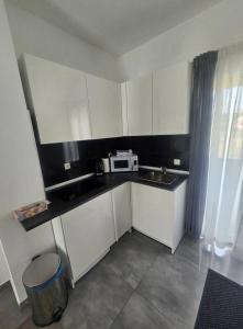 a small kitchen with white cabinets and a microwave at Apartman MAGDALENA in Sesvete