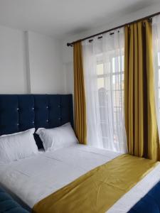 a bed with a blue headboard and a window at Relax Crib Nairobi in Nairobi