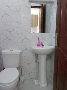 a white bathroom with a toilet and a sink at Relax Crib Nairobi in Nairobi +20 photos