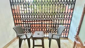 two chairs and a table in front of a fence at Muffys Baga Apartment in Baga