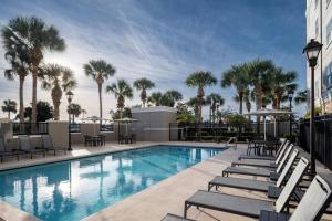a swimming pool with chaise lounge chairs and palm trees at Residence Inn Melbourne in Melbourne