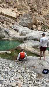 three people standing on rocks near a body of water at Wadi hawer tour guiding and local farm tour in Biḑ‘ah +4 photos