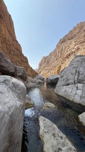 a river in a canyon with large rocks at Wadi hawer tour guiding and local farm tour in Biḑ‘ah