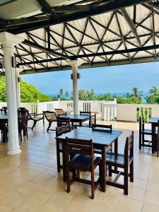 a patio with tables and chairs and a view of the ocean at French Residence Tangalle in Tangalle