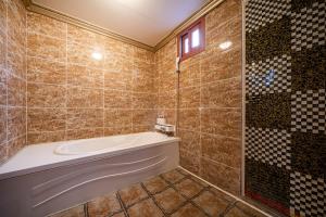 a tiled bathroom with a tub and a window at 센스모텔 in Sasang-yŏk