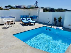 a blue swimming pool on a patio with a table and chairs at Villa Kamari in Kastraki