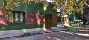 a green house with a brown door and a tree at La Guevarina- Casa de Campo in Tres Esquinas